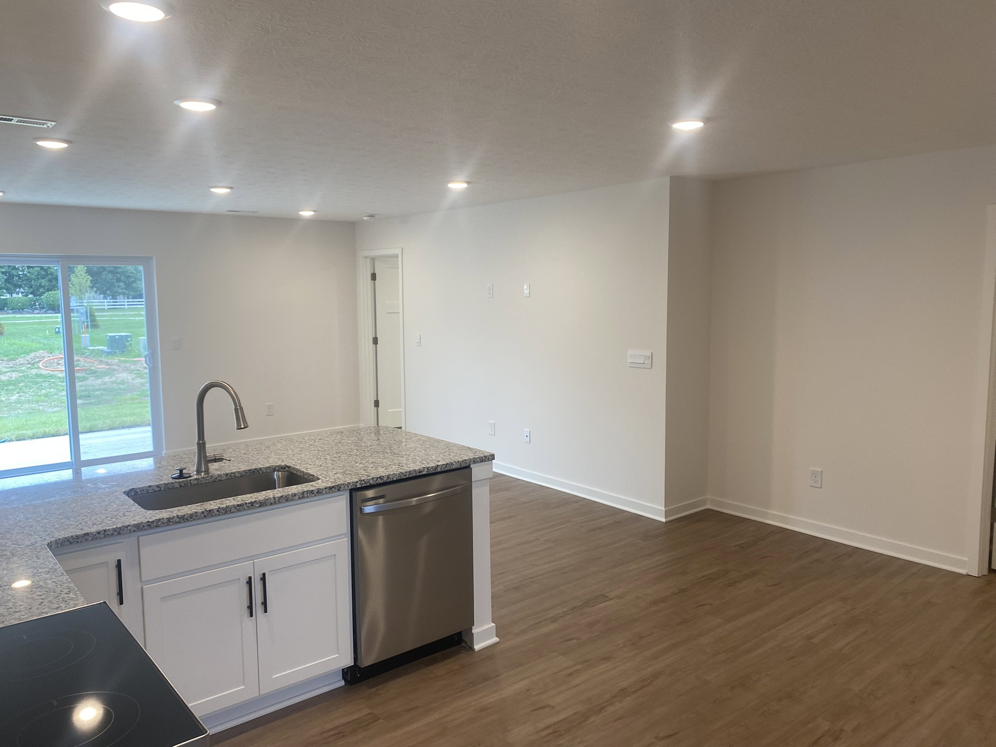 Modern kitchen with a granite countertop and open floor plan leading to a spacious living area.