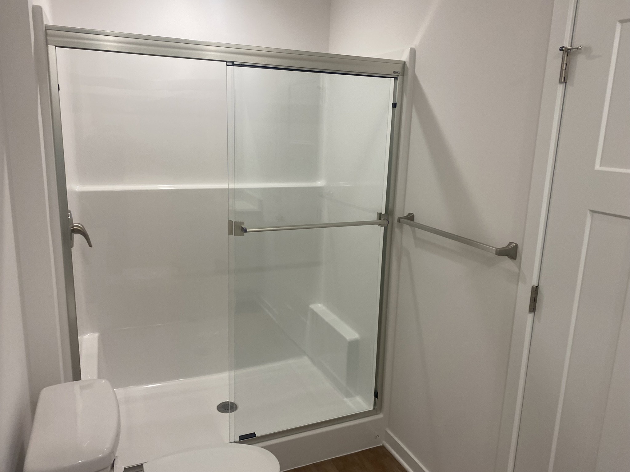 A modern bathroom with a clear glass shower enclosure and a white toilet.