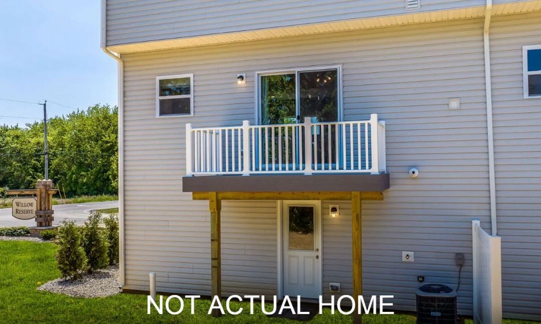 Side view of a modern gray townhouse with a small balcony and a sign indicating