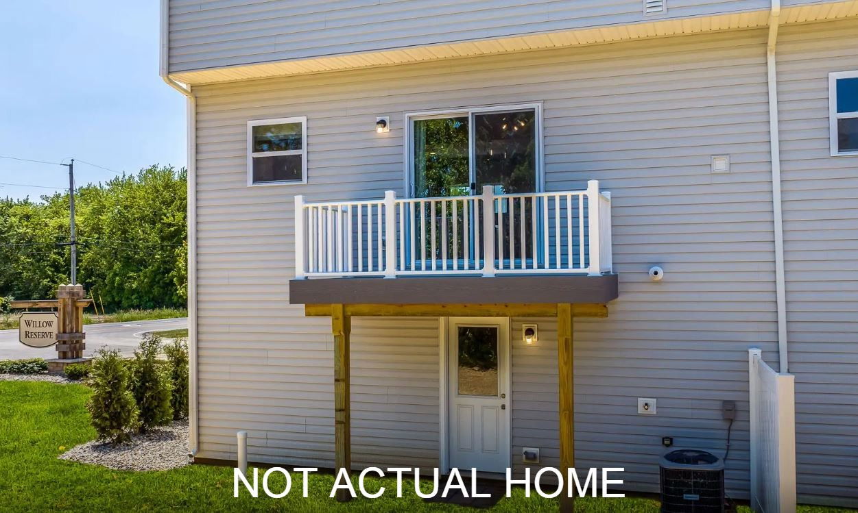 Exterior of a modern residential building with gray siding, featuring a white balcony and a sign for Willow Reserve.