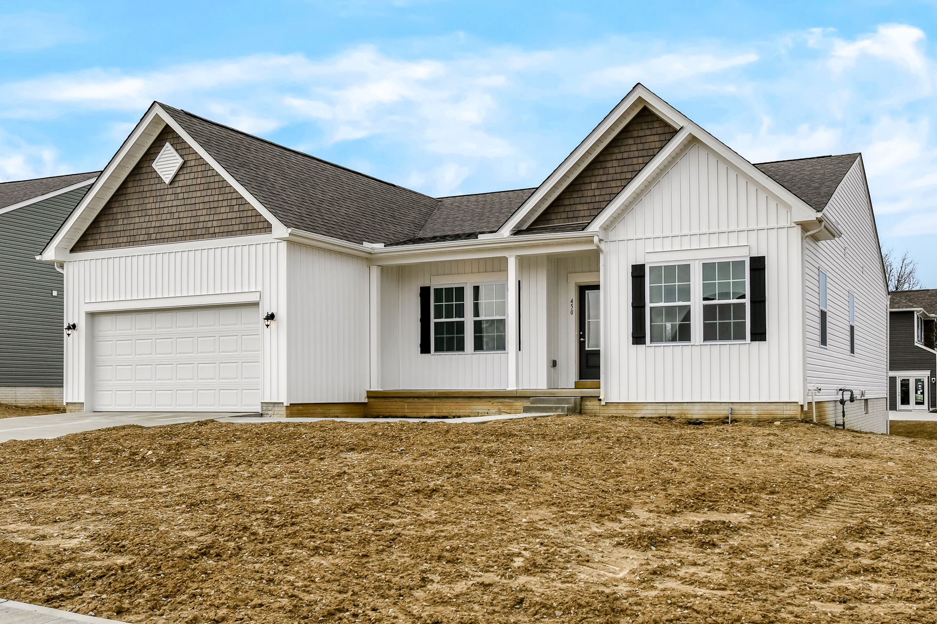 Newly constructed modern white house with an attached garage and pitched roof, set against a clear blue sky.
