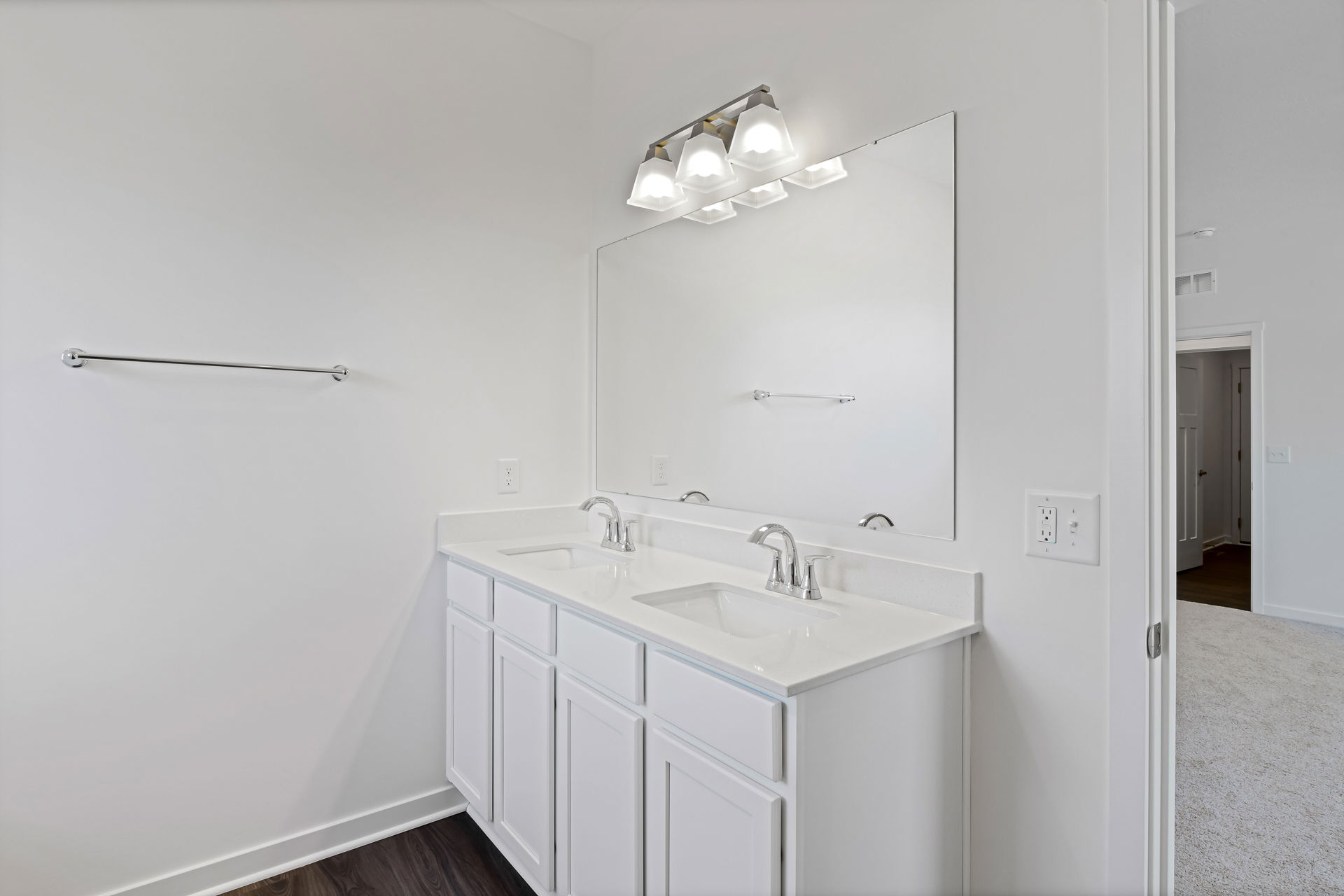 Modern white bathroom with a dual-sink vanity, large mirror, and overhead lighting.