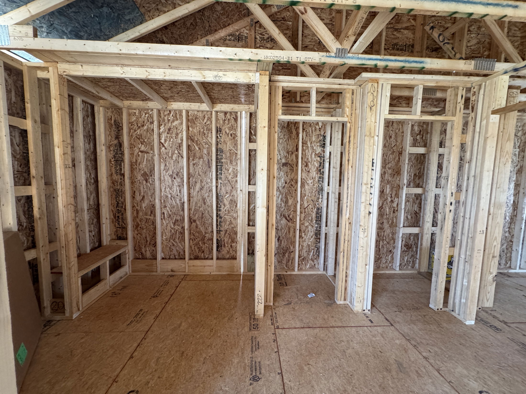 Framed interior of a new construction house showcasing wooden beams and plywood sheathing.