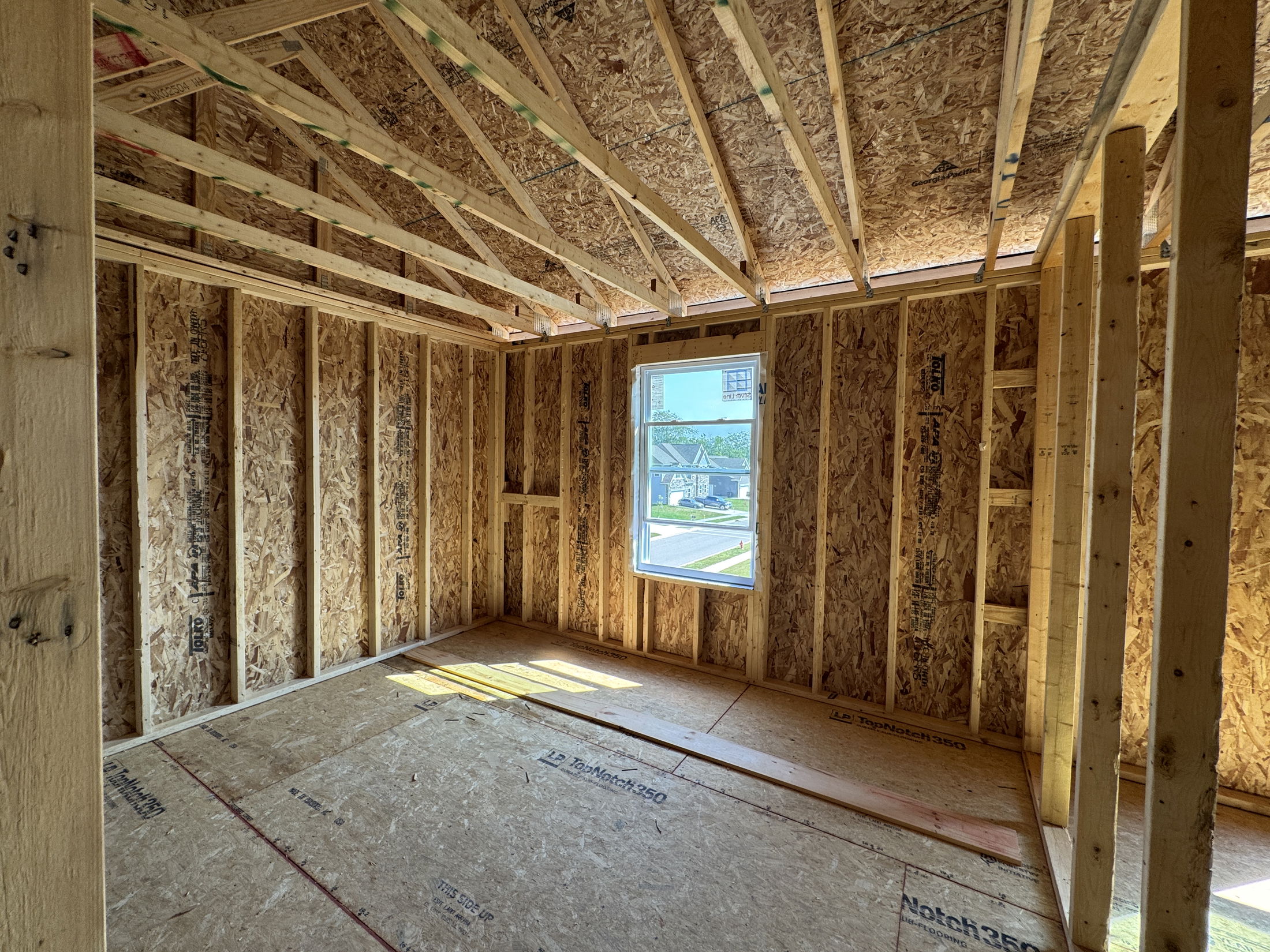 Partially constructed room featuring exposed wooden framing and a window, showcasing the early stages of residential construction.