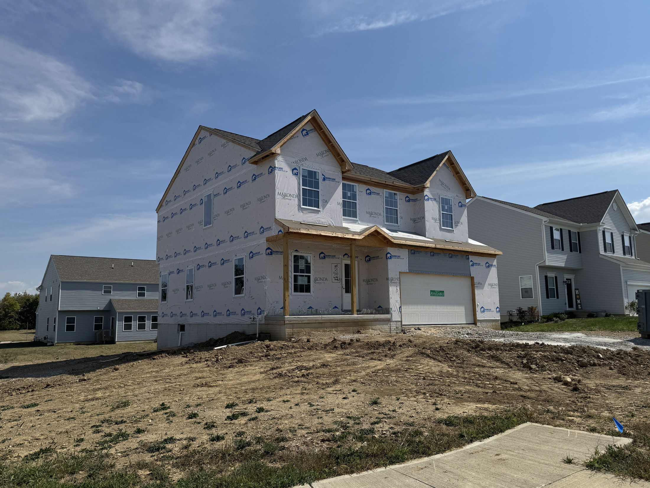 Newly constructed two-story house in a suburban neighborhood under clear blue skies.