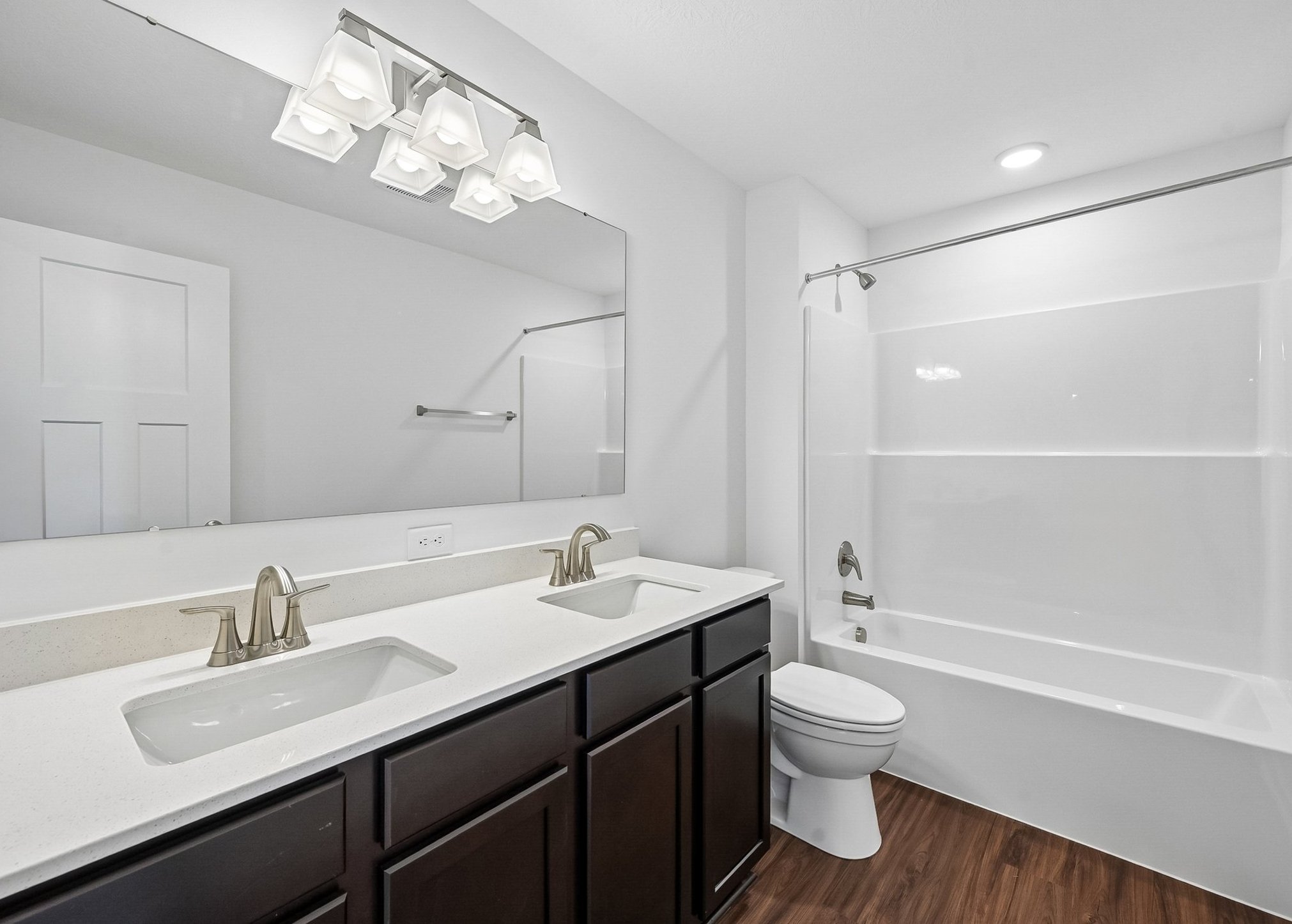 Modern bathroom featuring dual sinks, a large mirror, and a bathtub with a shower curtain.