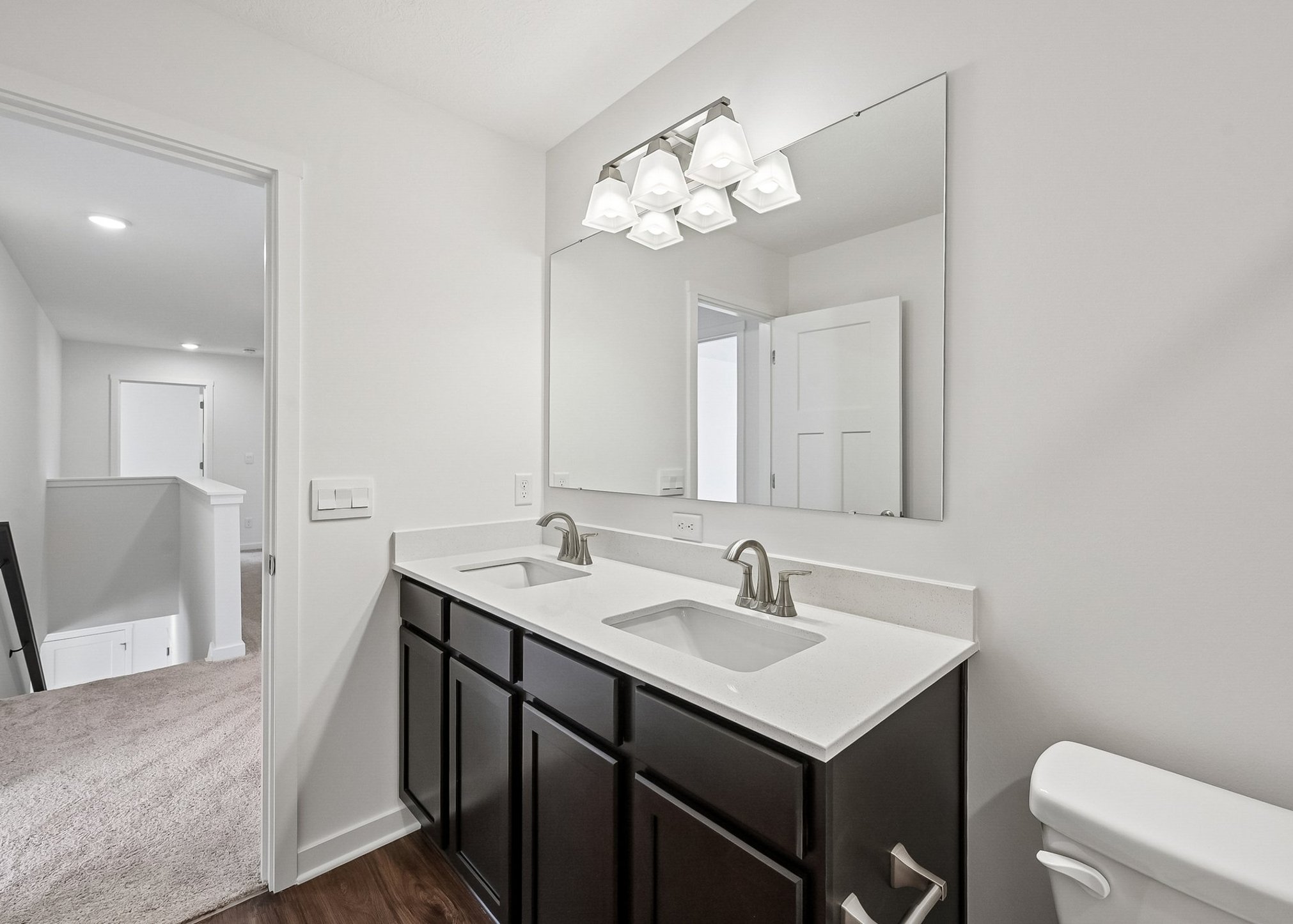 Modern bathroom featuring a double sink vanity with a large mirror and a light fixture above.