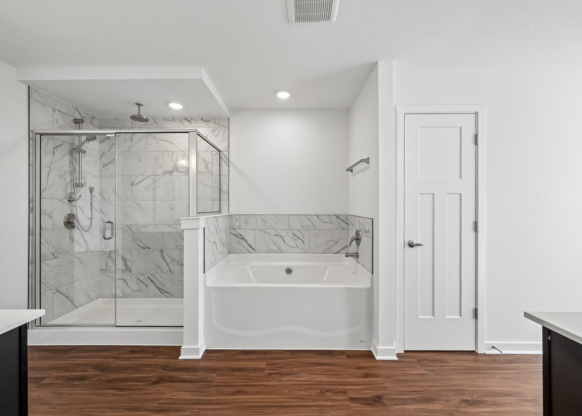 Modern bathroom featuring a glass shower, a freestanding tub, and marble tile accents.