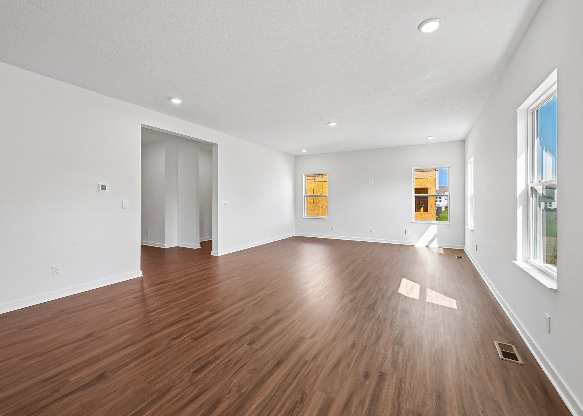 Spacious, empty room with hardwood floors and large windows providing natural light.
