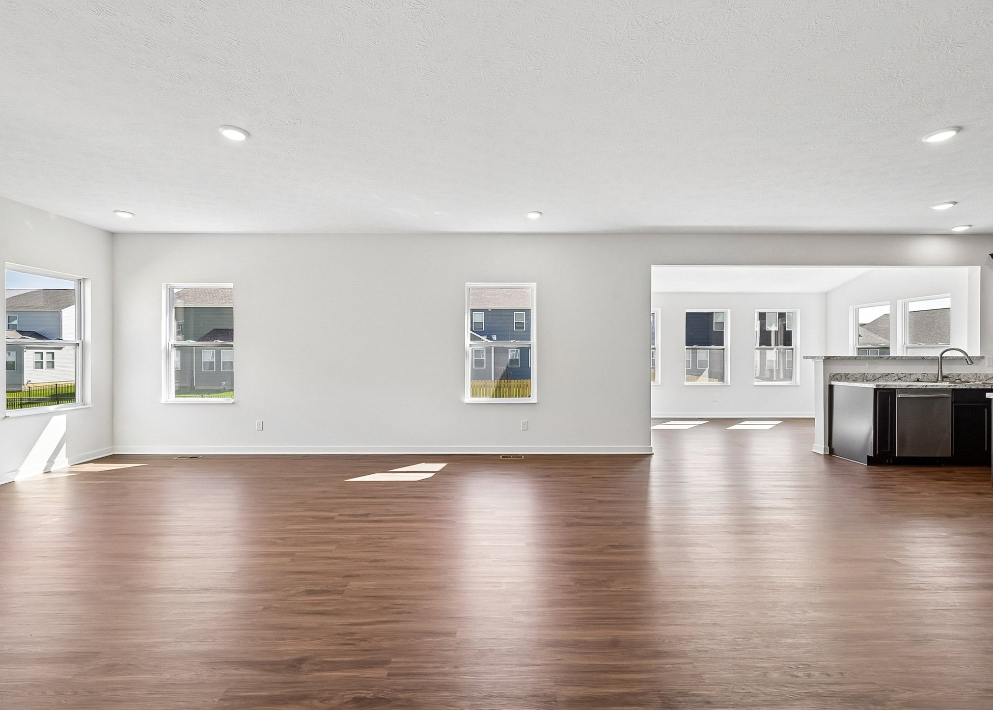 Spacious, modern living area with wood flooring and large windows allowing natural light.