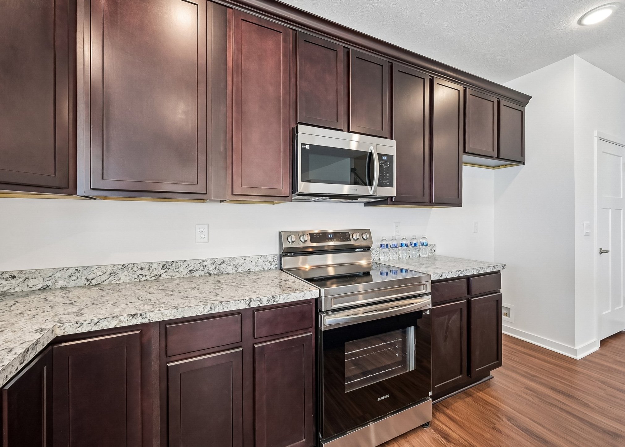 A modern kitchen featuring dark wood cabinets, stainless steel appliances, and a granite countertop.