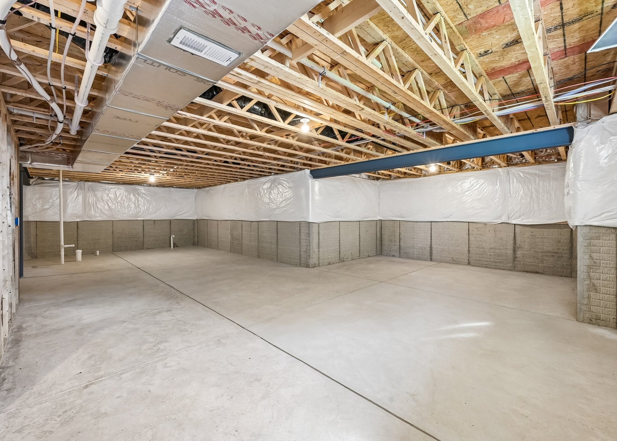Unfinished basement with exposed wooden beams and concrete walls.