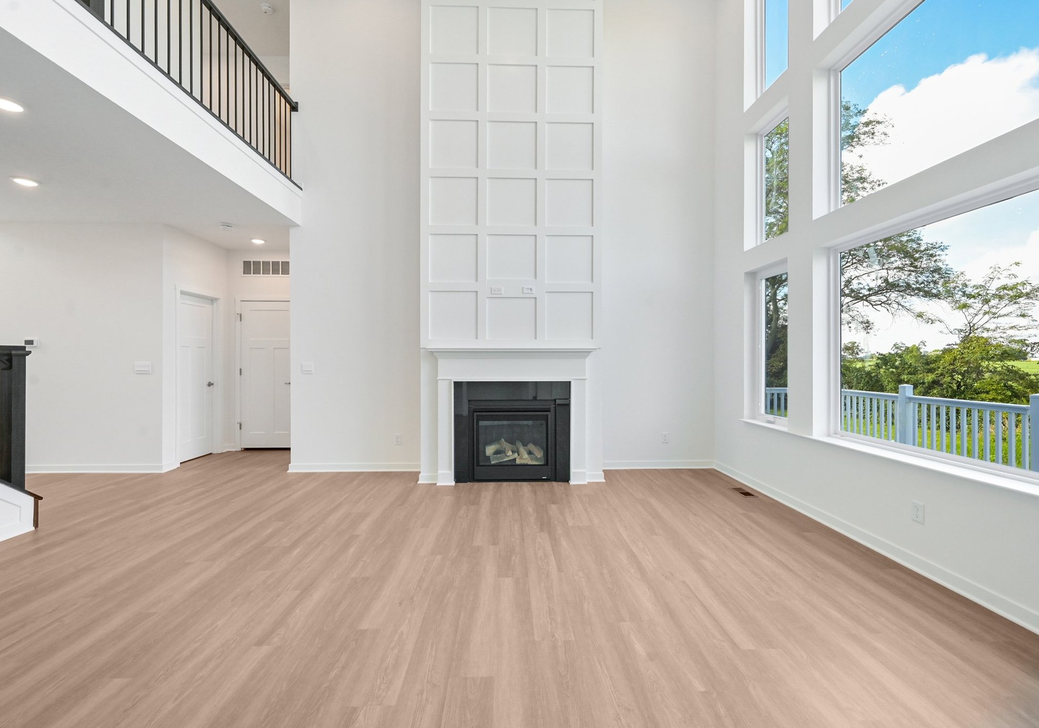 Spacious living room with high ceilings, a large fireplace, and expansive windows letting in natural light.