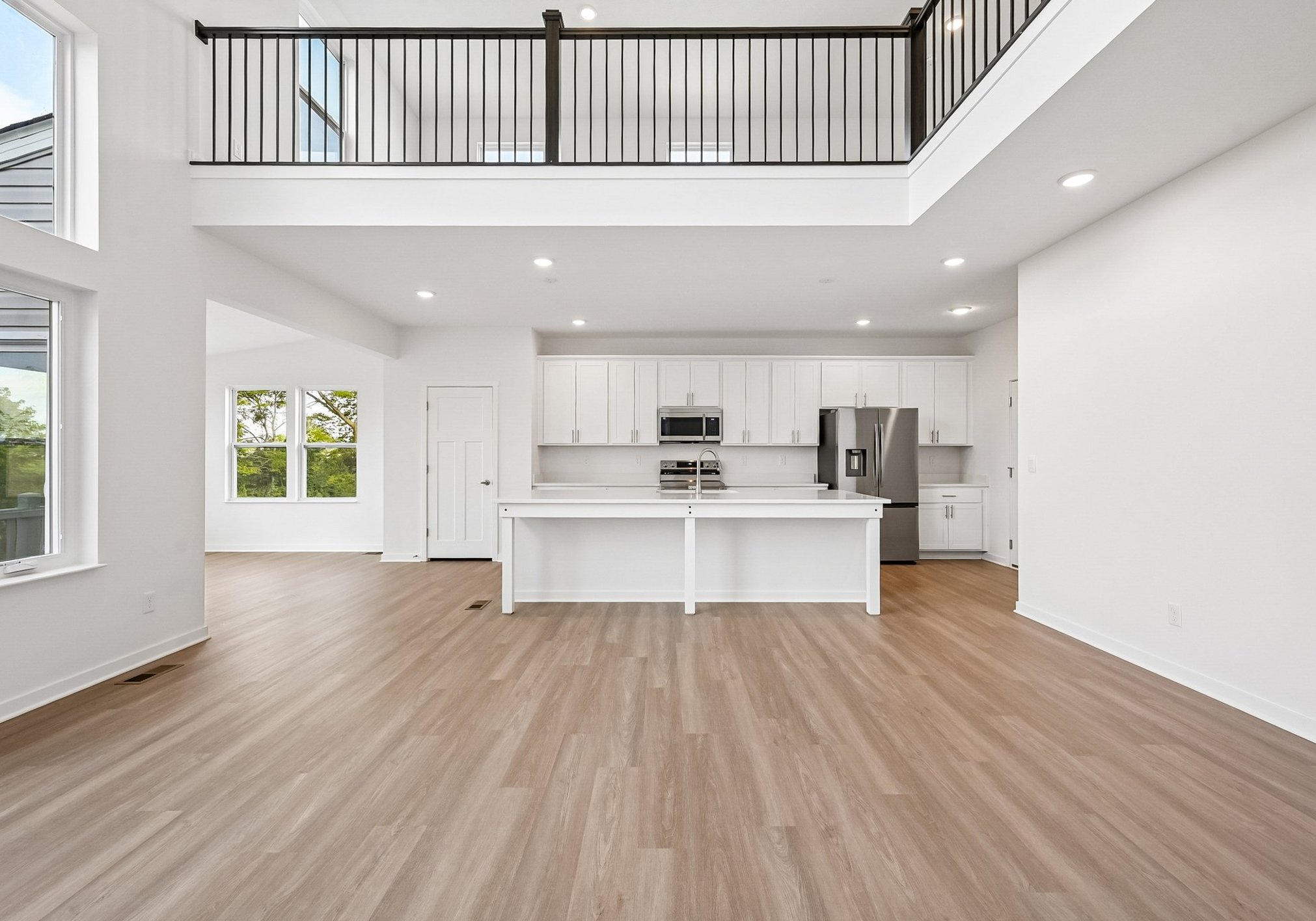 Spacious modern kitchen and living area with light wooden floors and high ceilings.