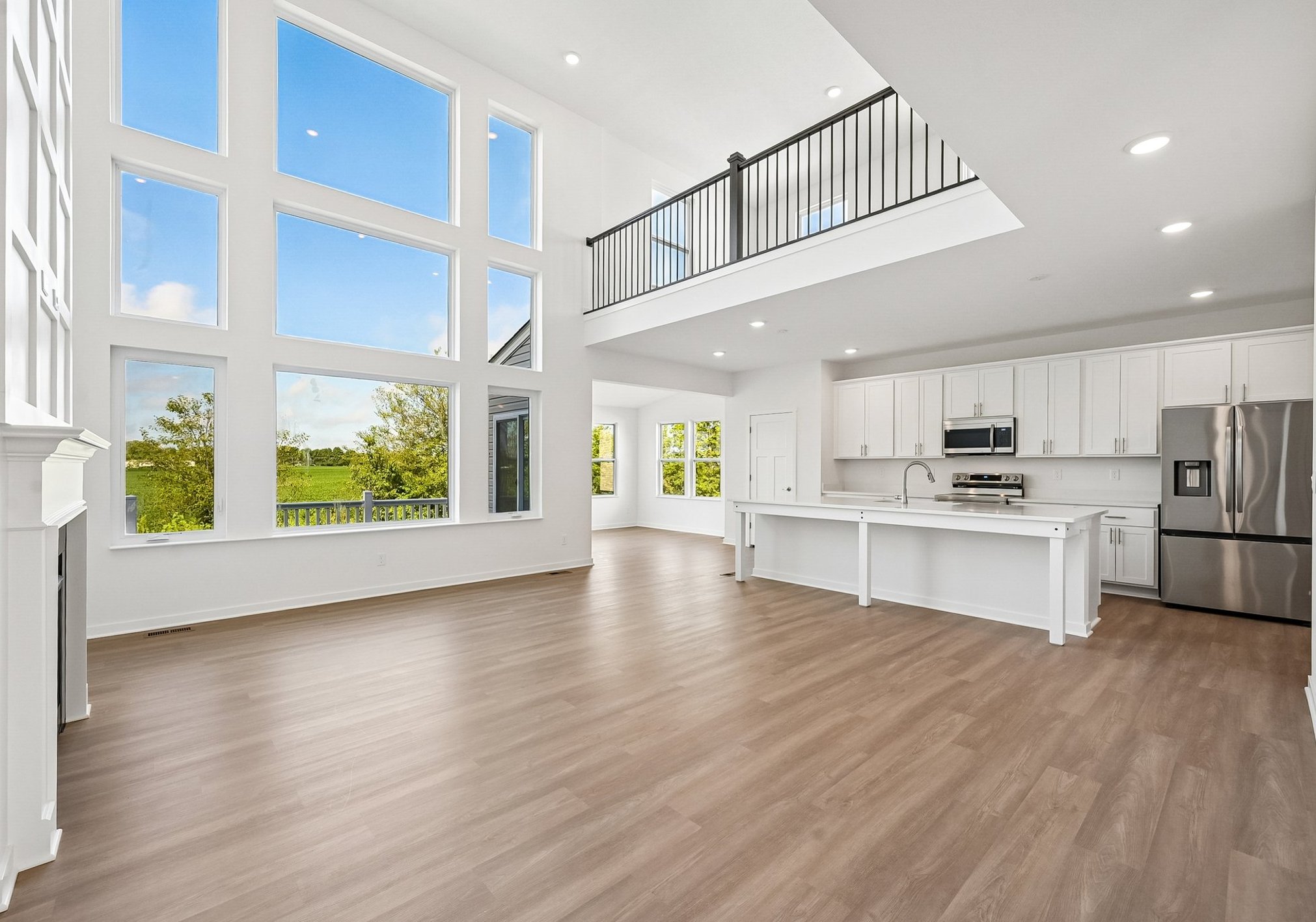 Spacious modern living area with large windows, high ceilings, and an open kitchen.