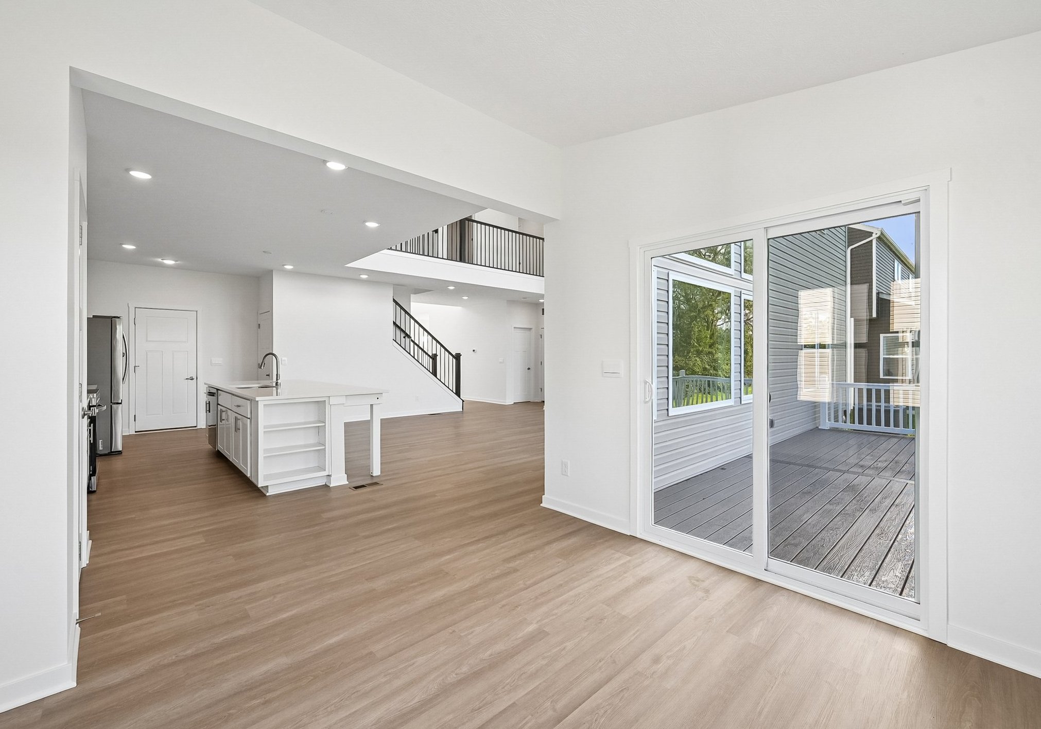 Bright, open-concept living area featuring a modern kitchen and sliding glass doors leading to a wooden deck.
