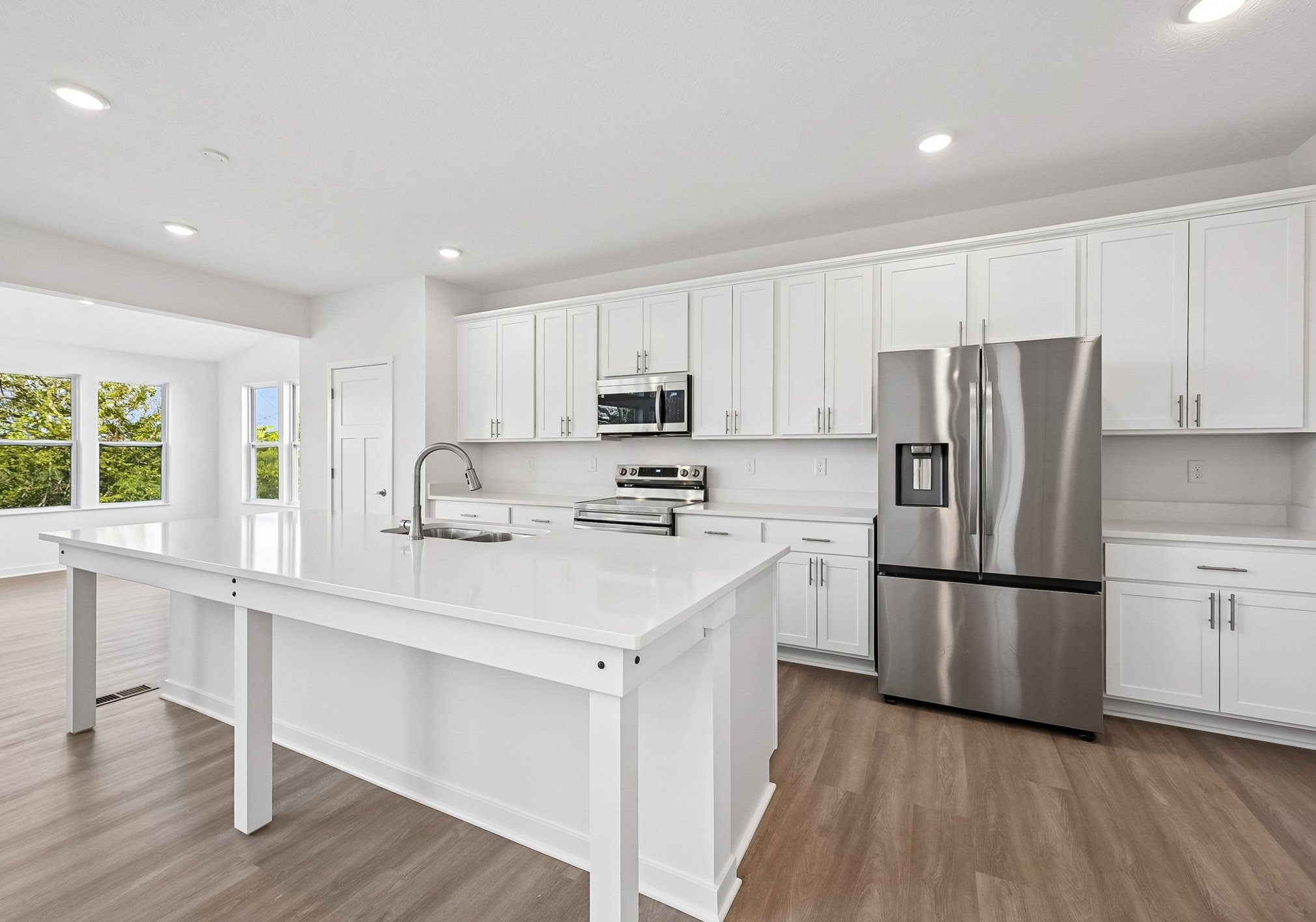 Modern kitchen with white cabinetry, stainless steel appliances, and a large island.