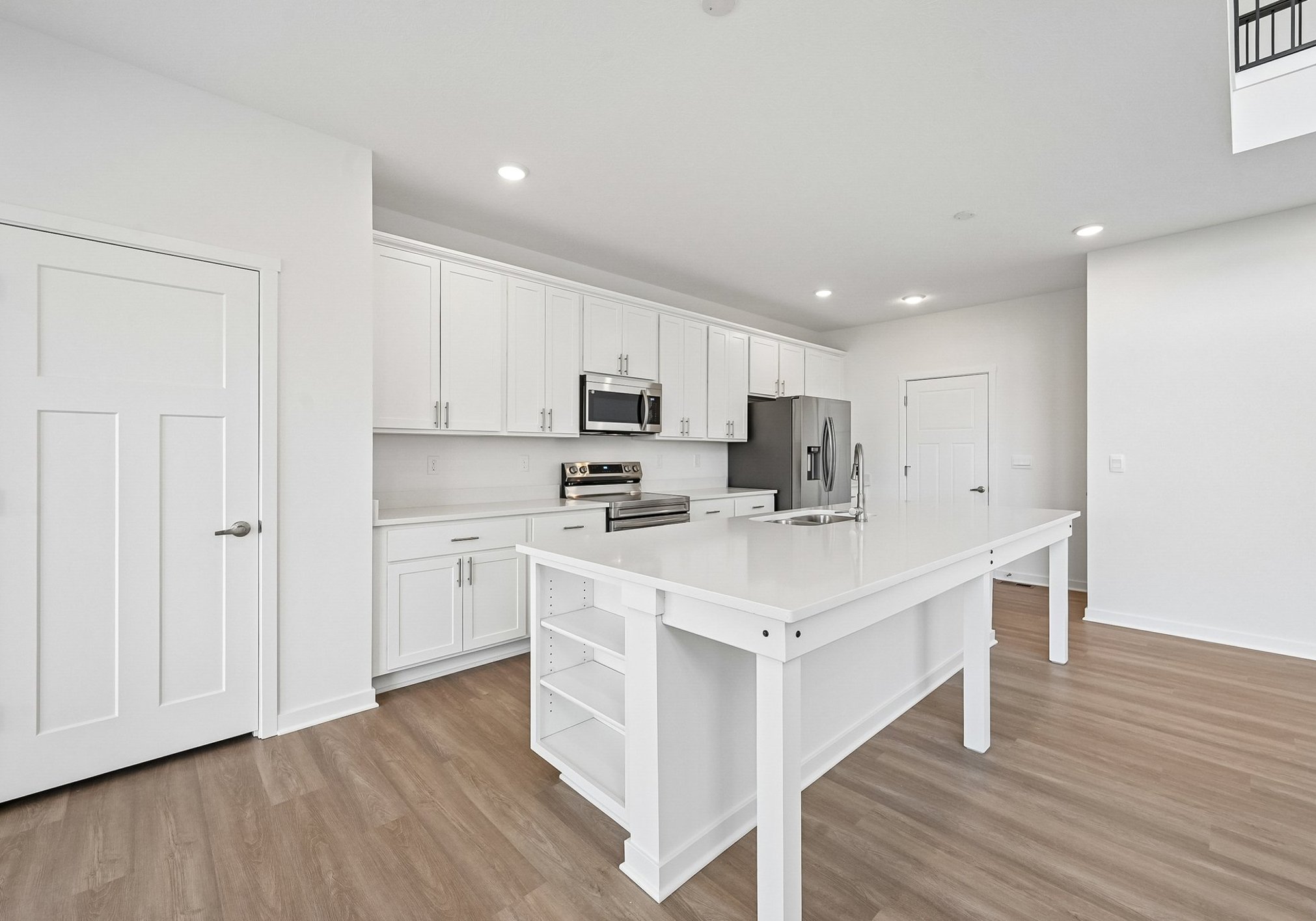 Modern kitchen featuring white cabinetry, stainless steel appliances, and a large central island with a sink.
