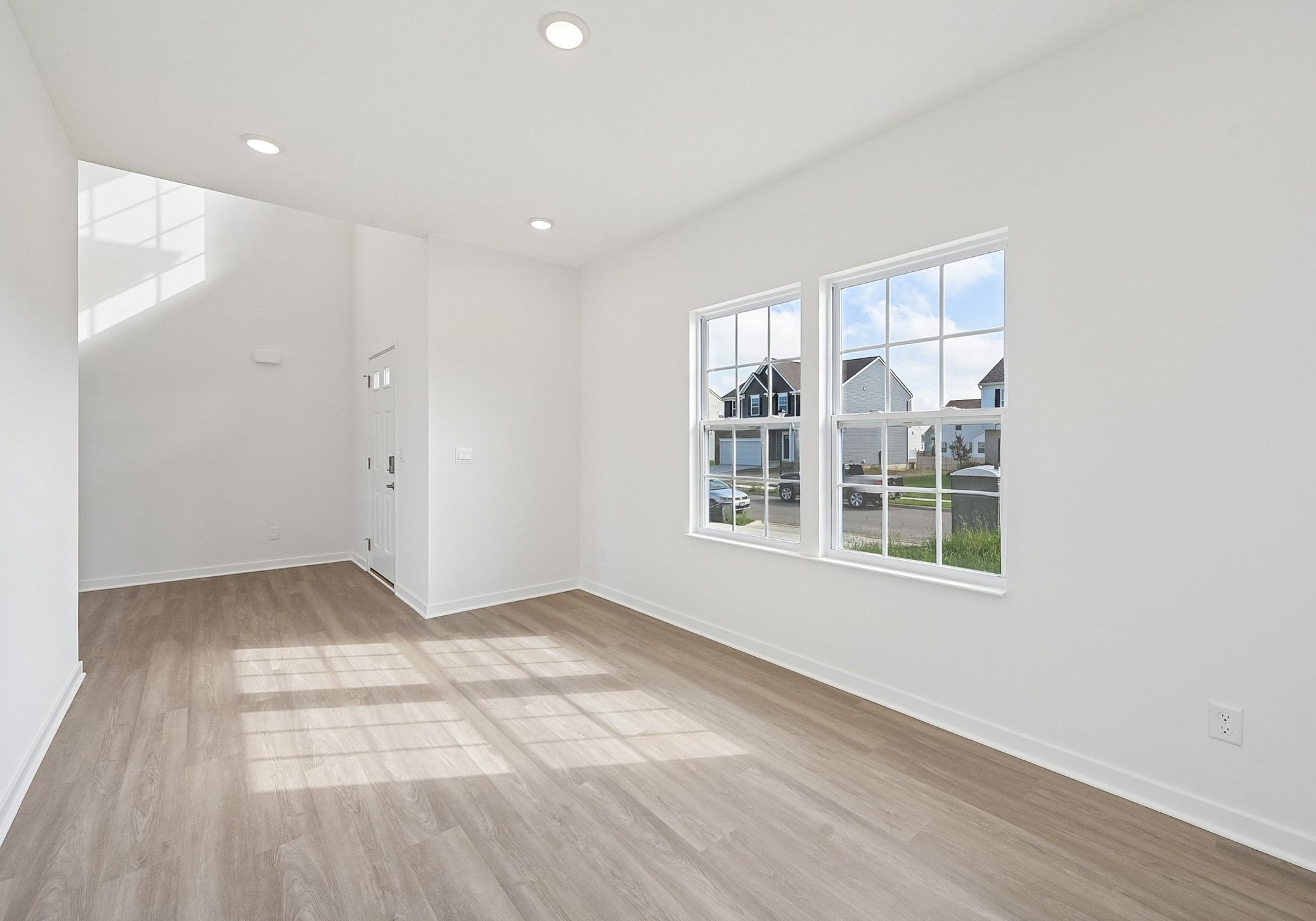 Bright, empty room with large windows and light-colored flooring.