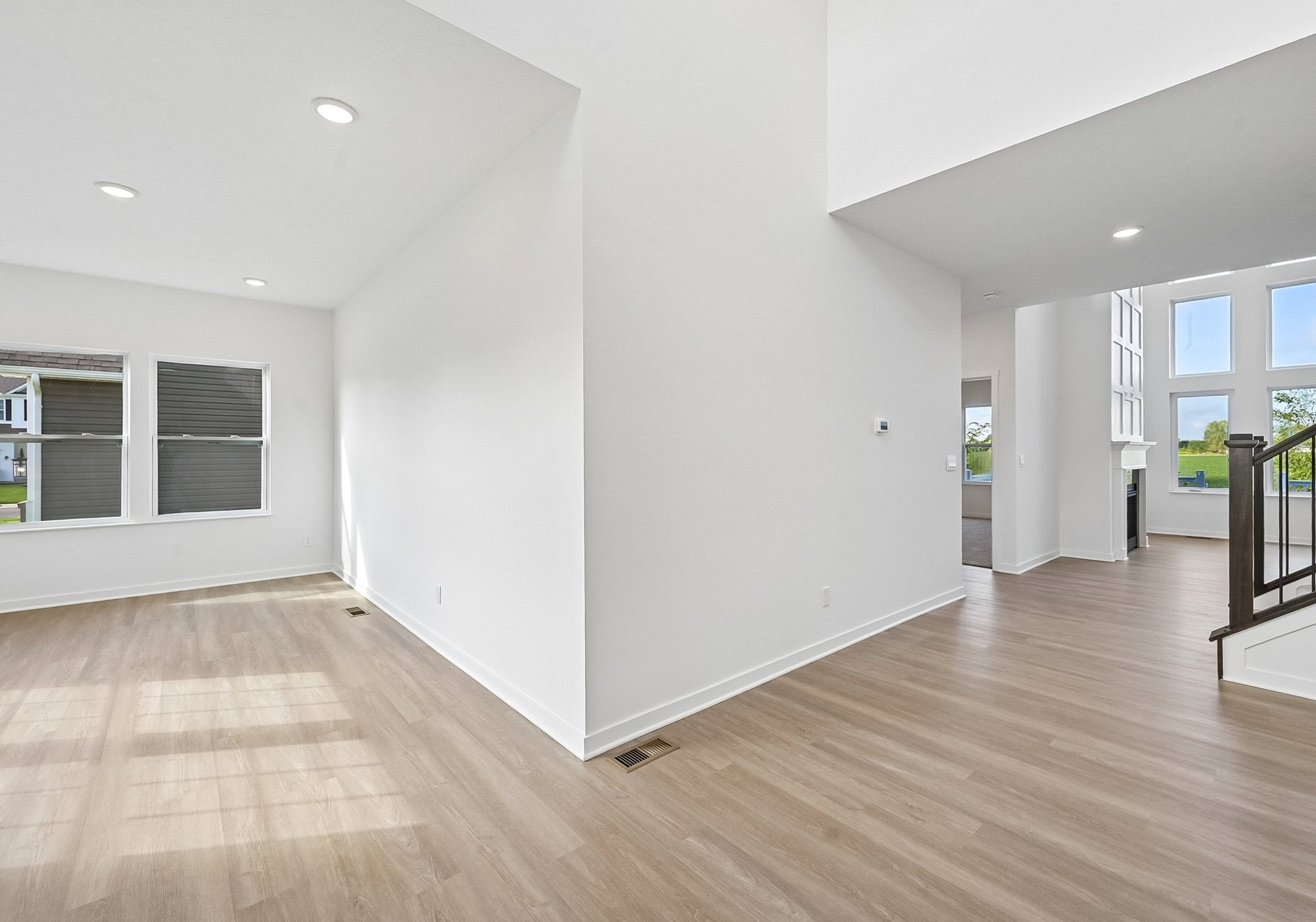 Bright, modern interior of a spacious, unfurnished living area with large windows and light wood flooring.