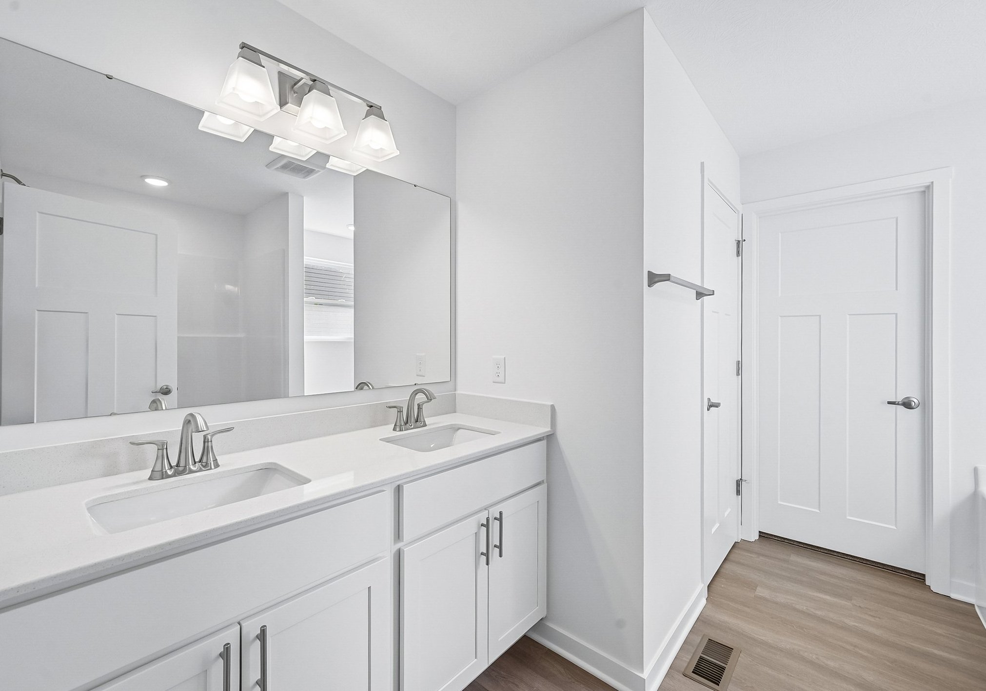 Modern bathroom featuring dual sinks, a large mirror, and a minimalist design.