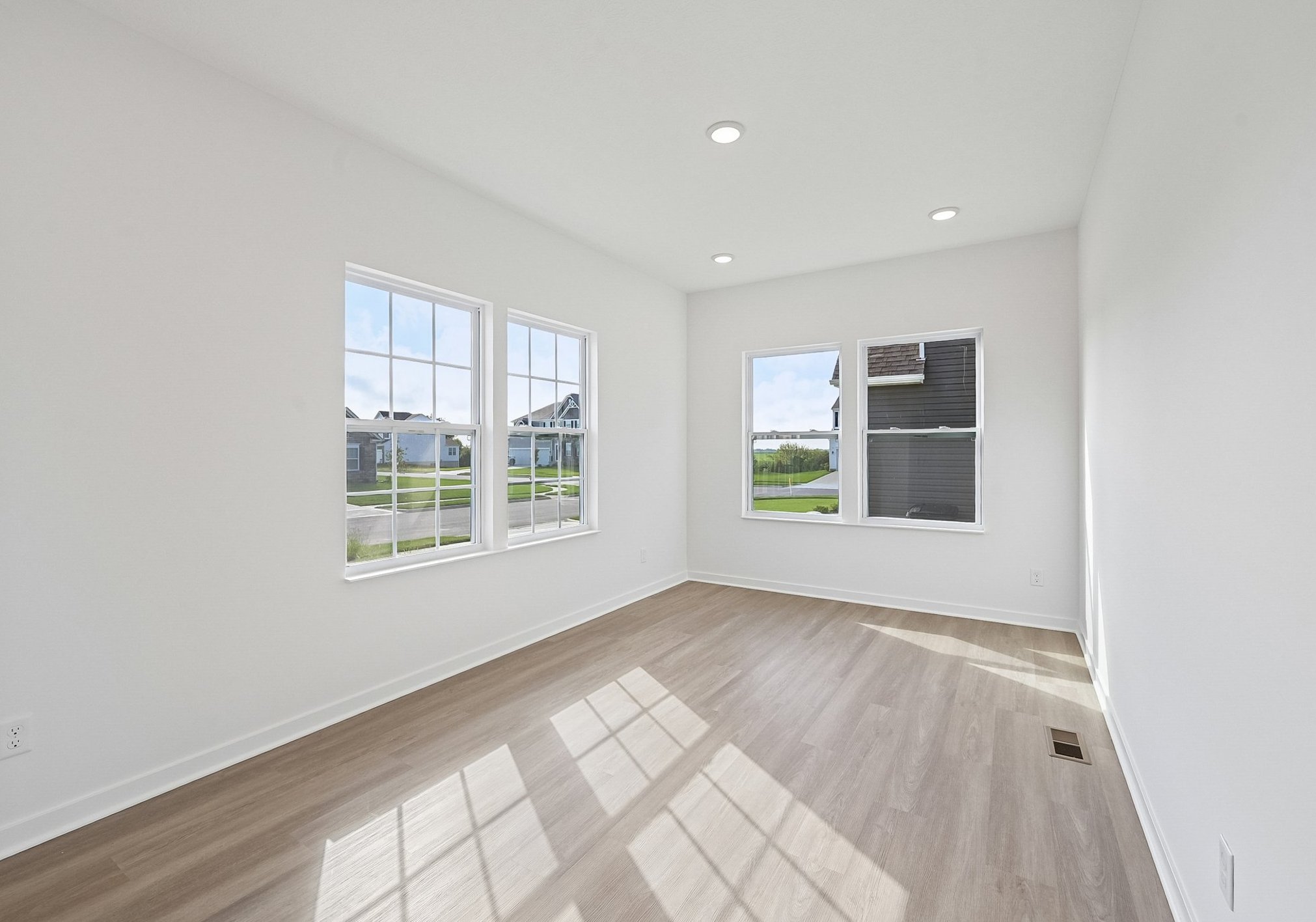A bright, empty room with large windows and light-colored walls and flooring.