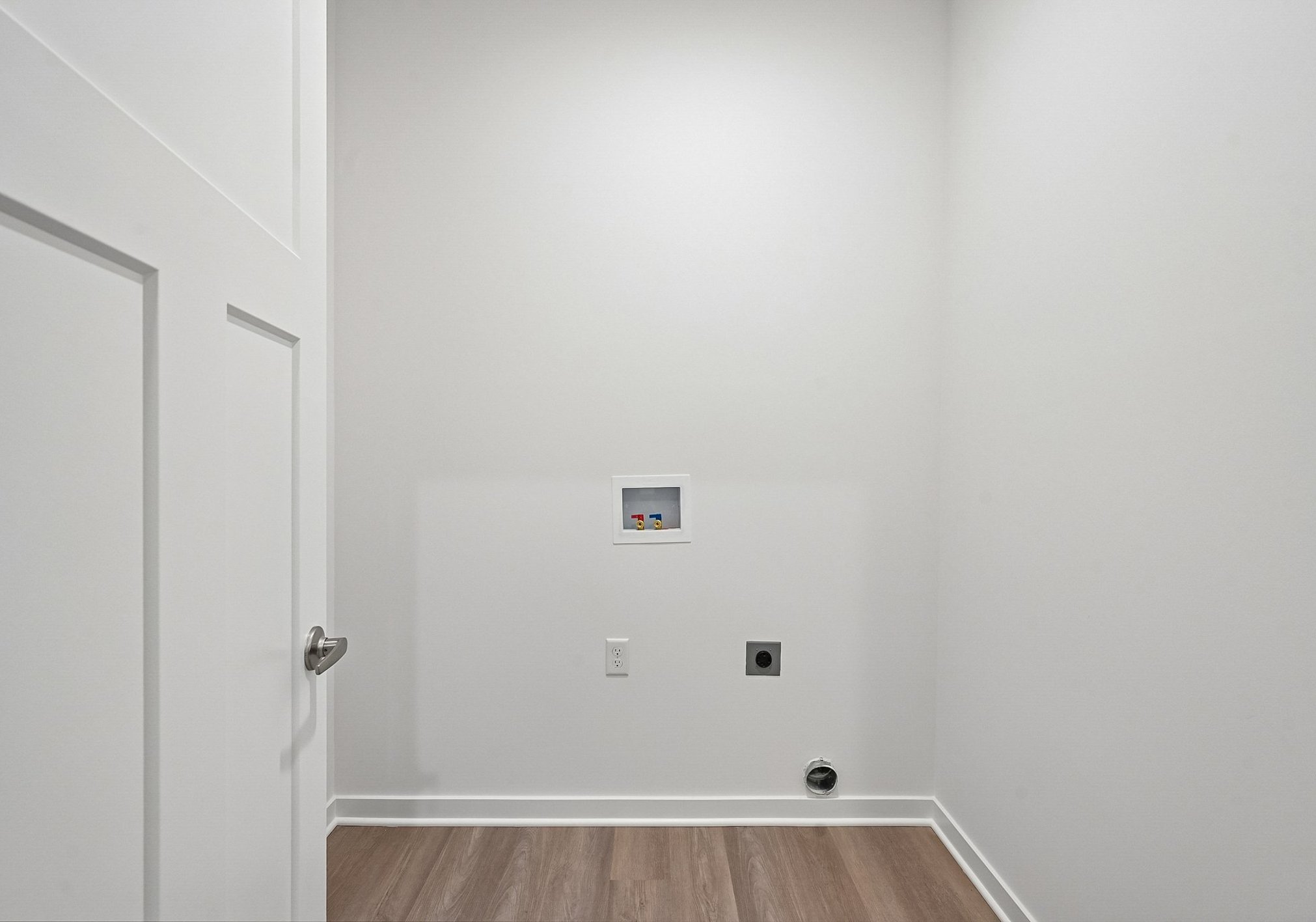 Empty room with light gray walls, a wooden floor, and a wall-mounted electrical panel.
