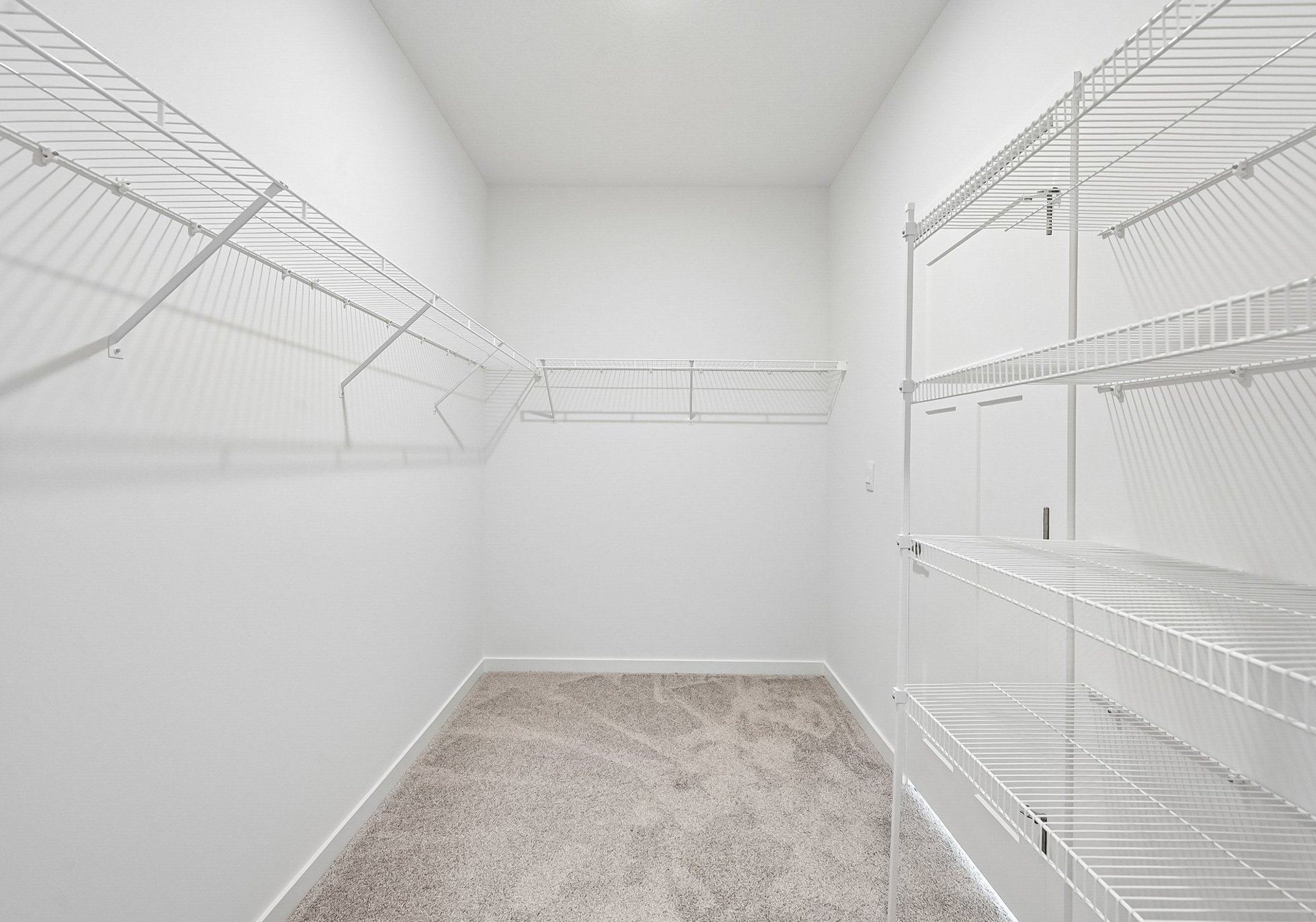 Empty closet with white wire shelving and carpeted floor.
