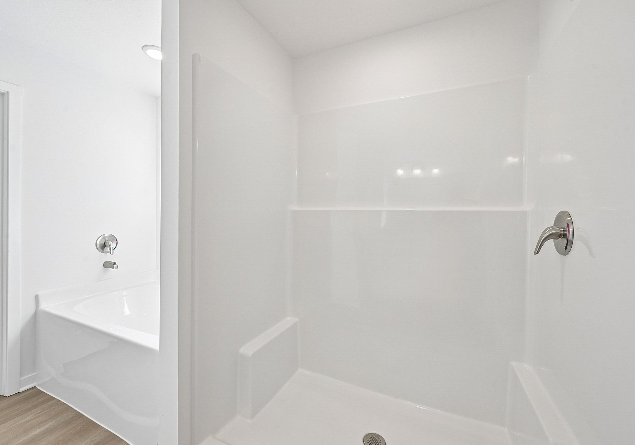 Bright, empty bathroom with a white shower and bathtub.
