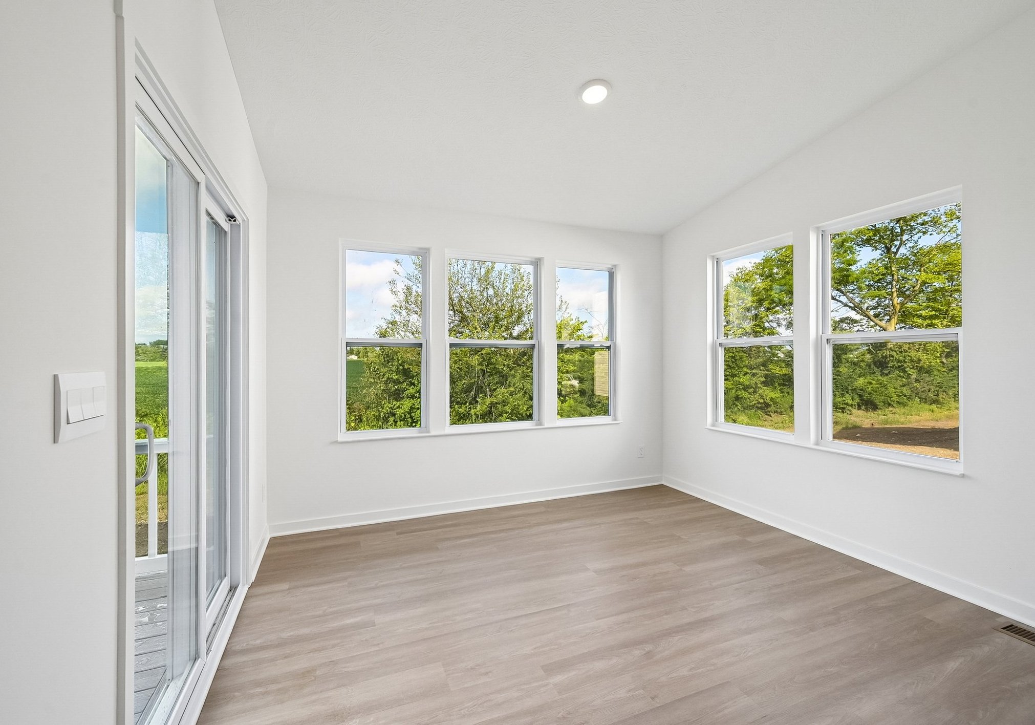 Bright, empty room with large windows overlooking greenery.