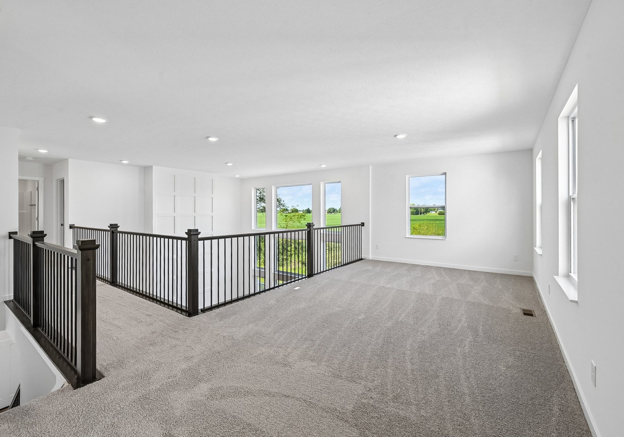Bright, open space with carpeted flooring and large windows overlooking a green landscape.