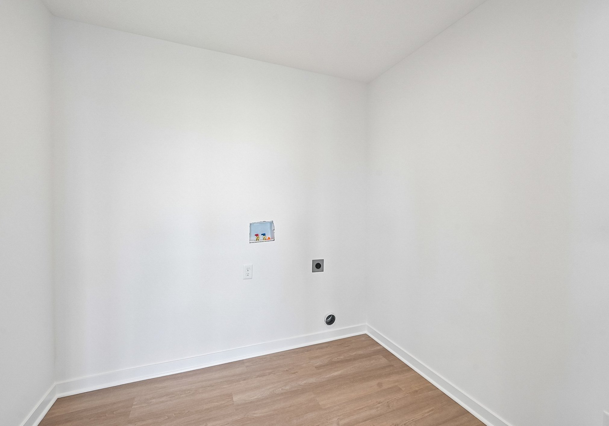 Empty room with light-colored walls and hardwood flooring.
