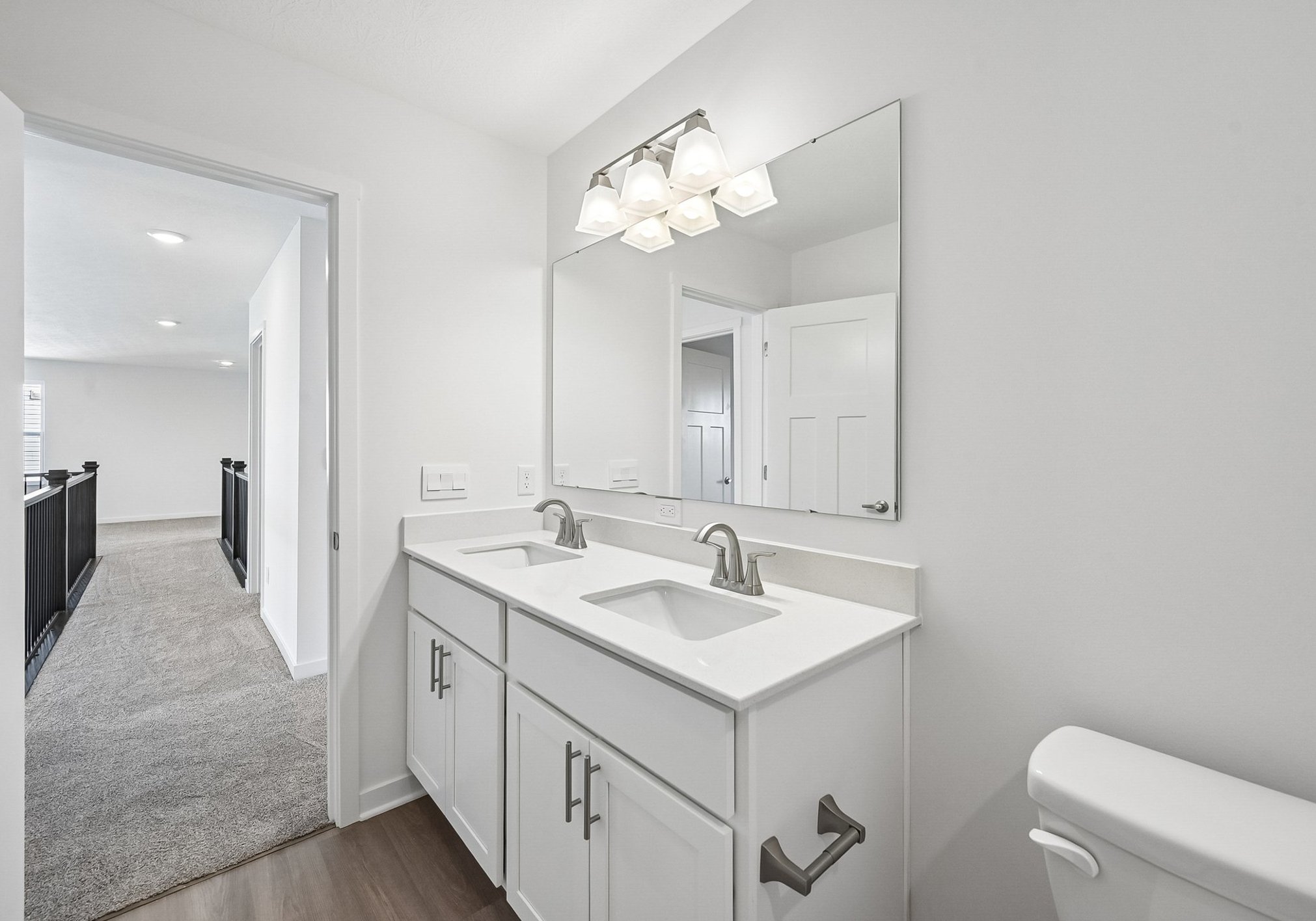 Modern bathroom featuring double sinks, a large mirror, and neutral-colored walls.